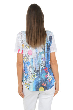 Woman wearing a colorful graphic t-shirt with a white background. Back shot.