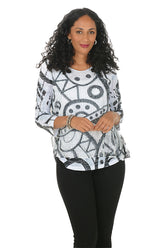 Woman wearing a patterned top and black pants on a white background.