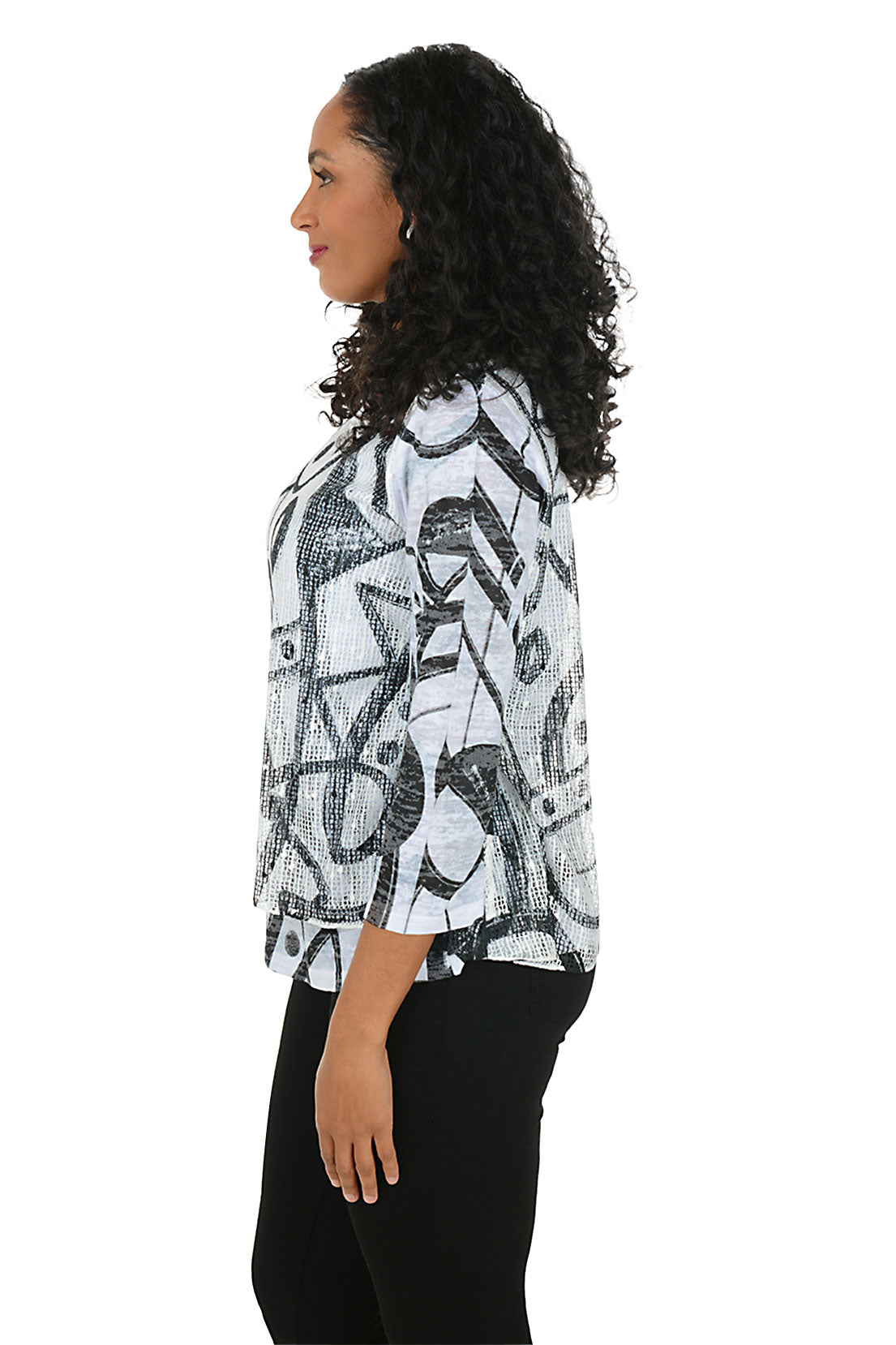 Woman wearing a patterned top and black pants on a white background. Side shot.