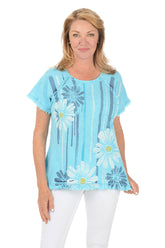 Woman wearing a light blue floral patterned top on a white background.