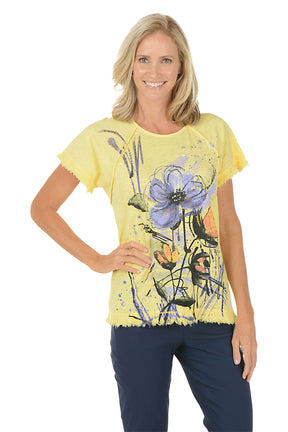 A woman wearing a short sleeve yellow shirt with a floral pattern.