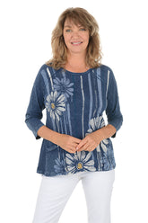 A woman wearing a blue 3/4 sleeve shirt with a daisy pattern.