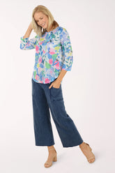 Woman wearing a colorful floral blouse and blue jeans on a white background