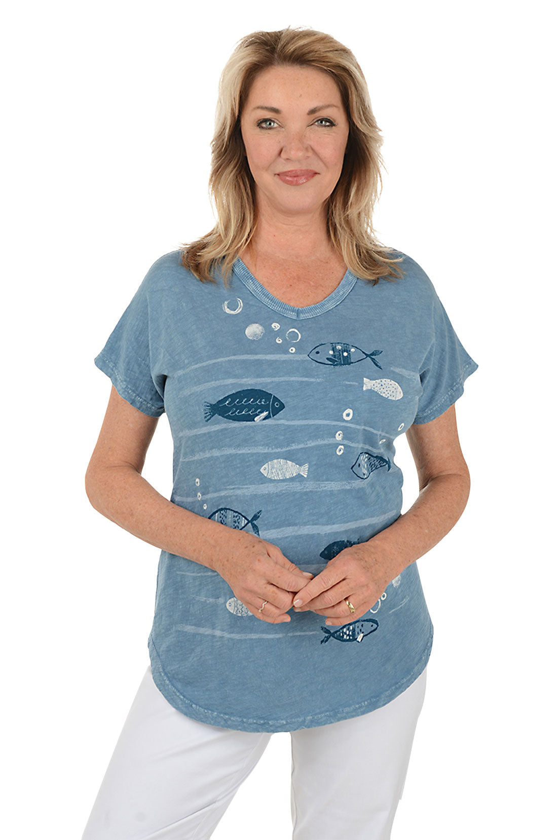 Woman wearing a blue t-shirt with fish designs on a white background.