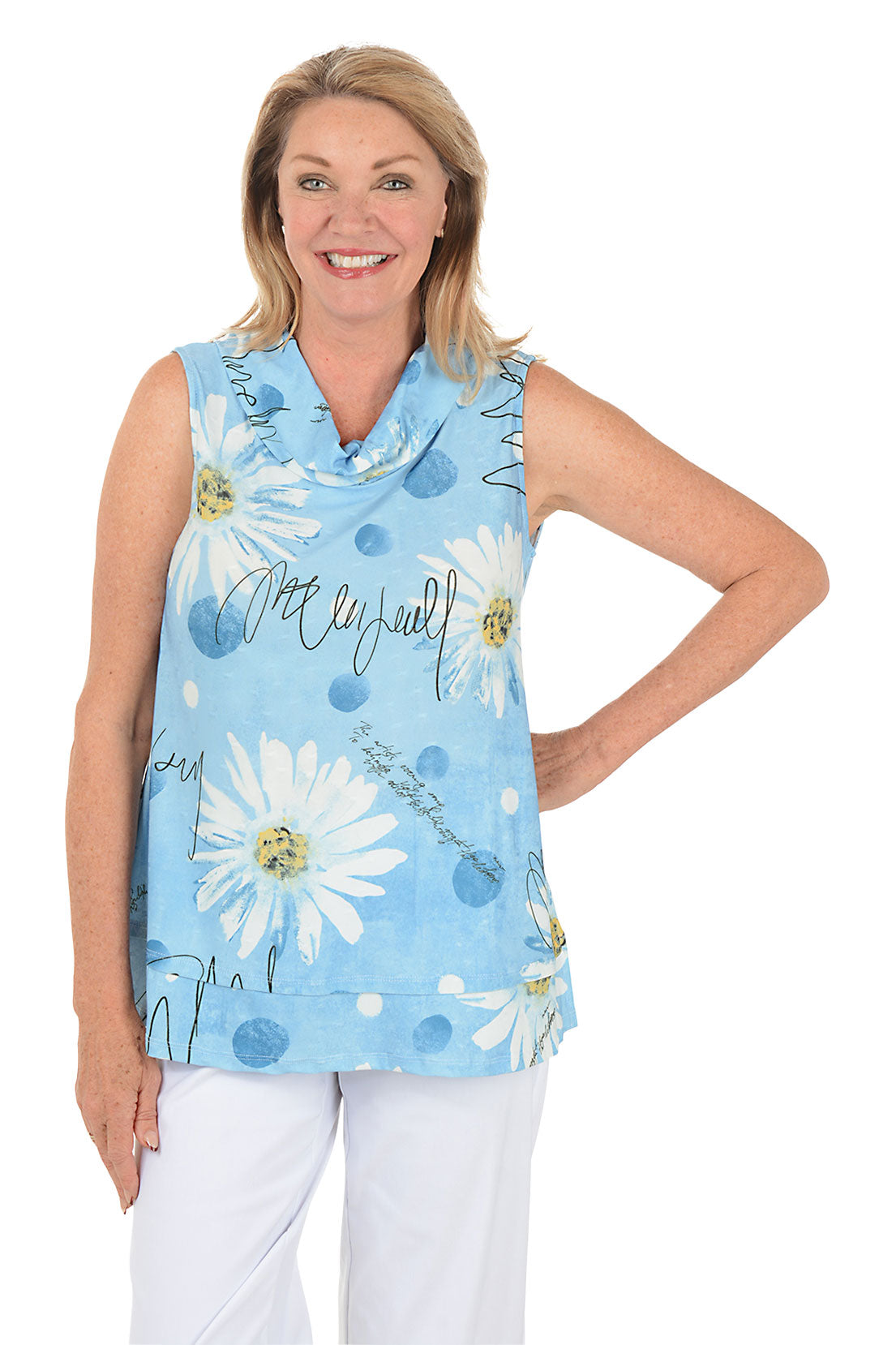 Woman wearing a sleeveless blue floral top with white pants on a white background.