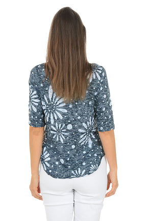 Woman wearing a blue floral patterned top on a white background. Back shot.