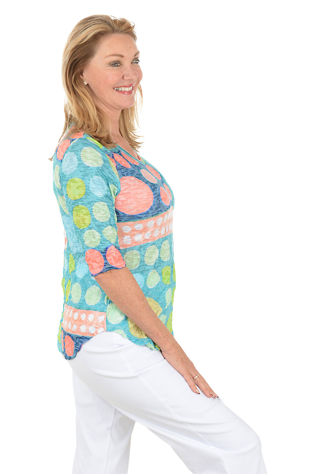 Woman wearing a colorful patterned top on a white background. Side shot.