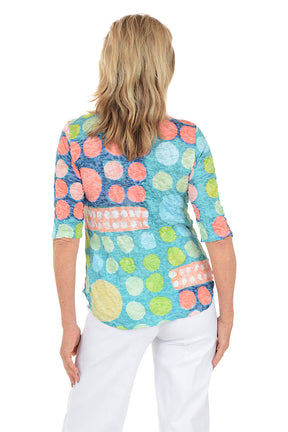 Woman wearing a colorful patterned top on a white background. Back shot.