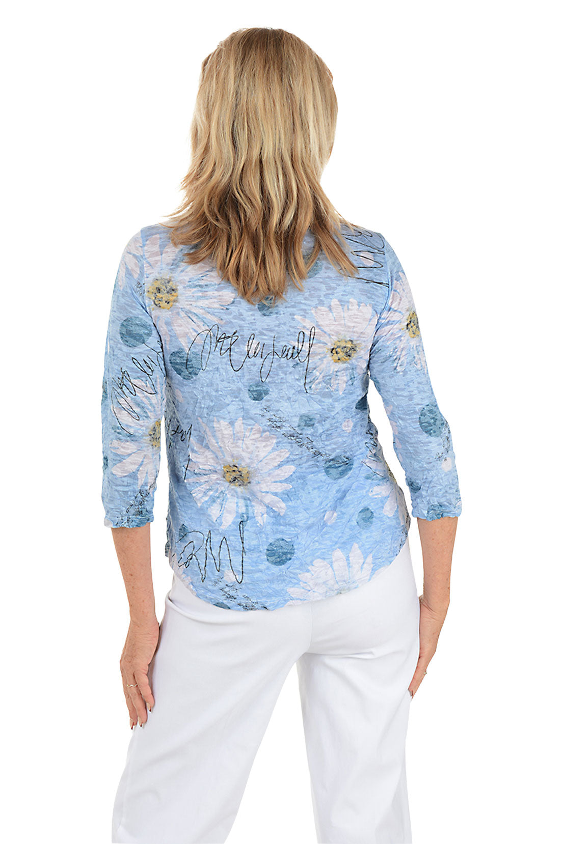 Woman wearing a blue floral blouse with white pants on a white background. Back shot.
