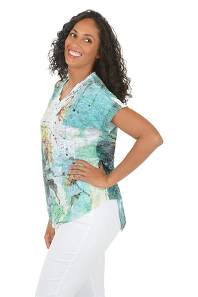 Woman wearing a floral-patterned top and white pants on a white background. Side shot.