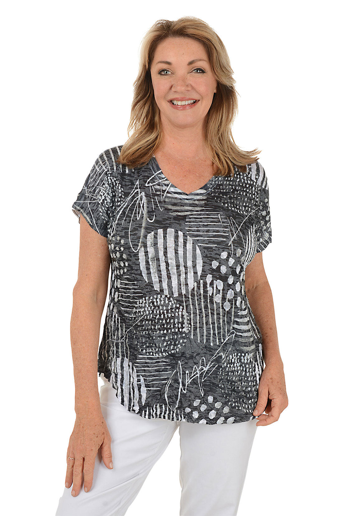 Woman wearing a black and white patterned top with white pants on a white background