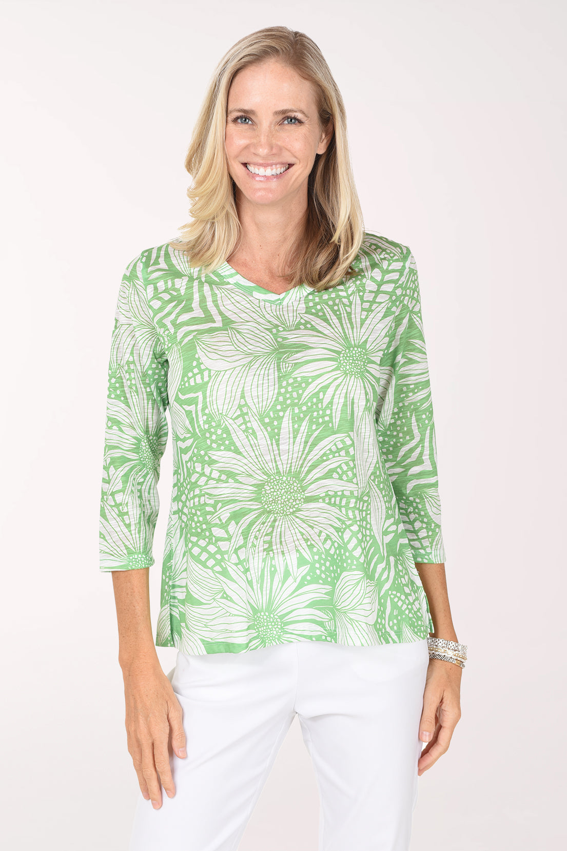 Model wearing the Jess and Jane Block Lightweight V-Neck Top, a bold green and white leaf print, over white pants, front view