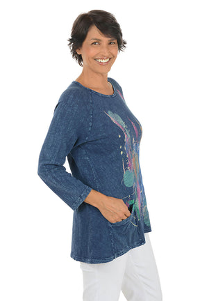 A side shot of a woman wearing a blue denim shirt with colorful design on a white background