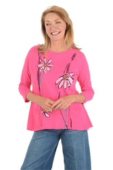 Woman wearing a pink long-sleeve top with floral designs on a white background.