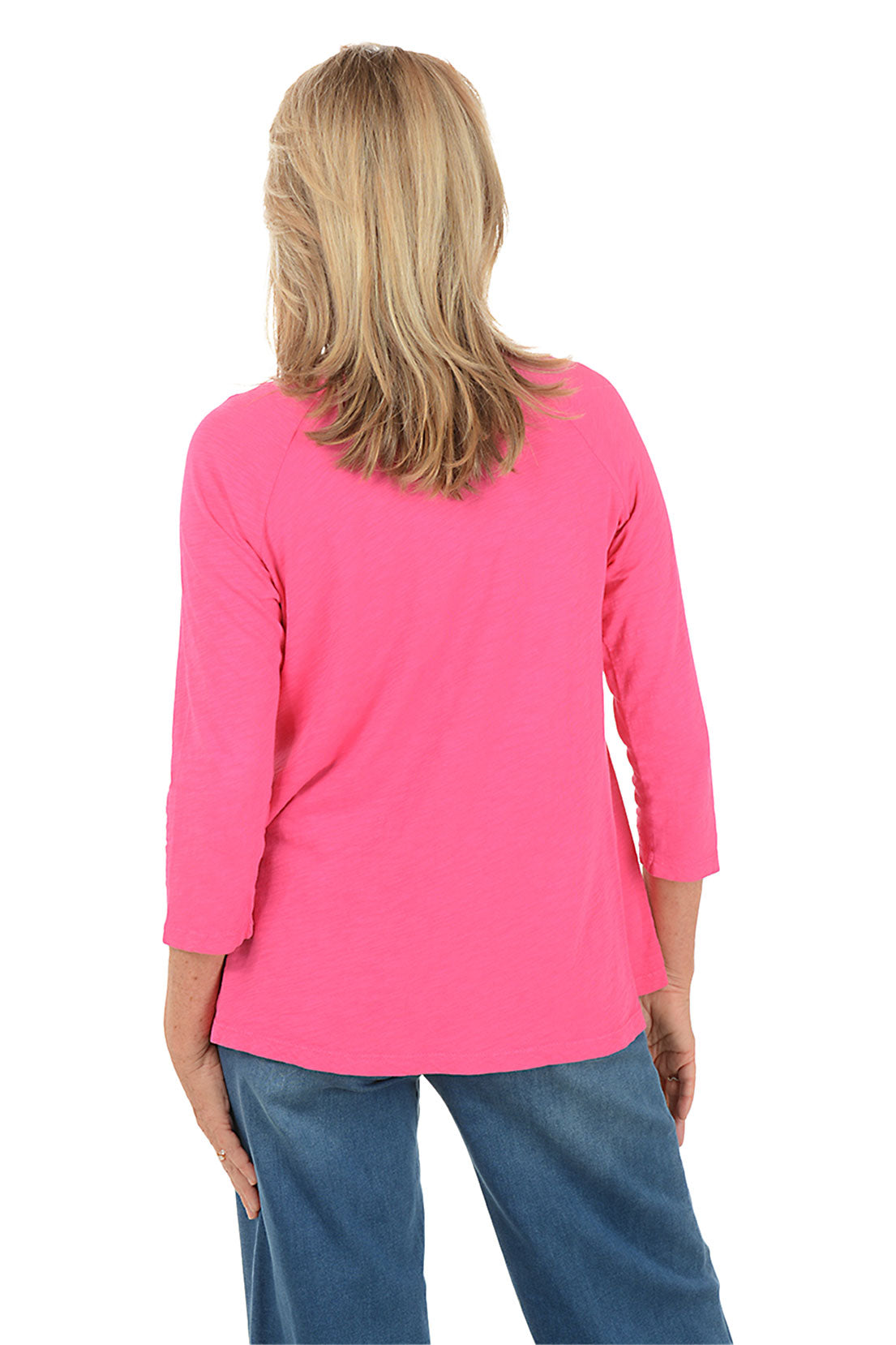 Woman wearing a pink long-sleeve top with floral designs on a white background. Back shot.