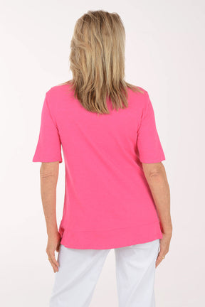 Woman wearing a pink blouse with floral patterns on a white background