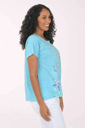 Woman wearing a blue t-shirt with colorful starfish designs on a white background