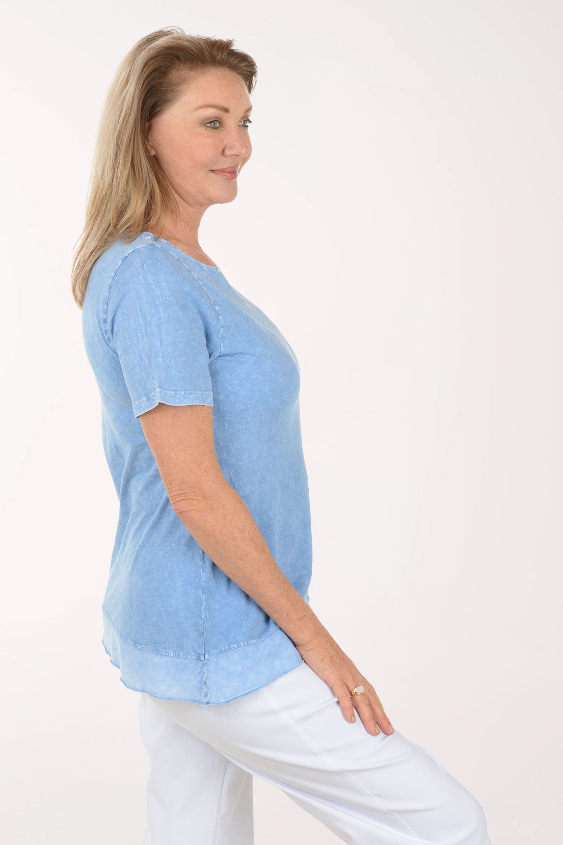 Woman wearing a light blue top and white pants on a white background