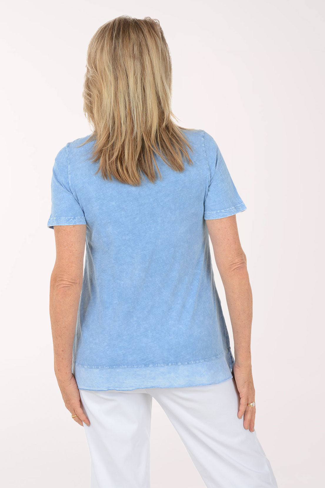 Woman wearing a light blue top and white pants on a white background