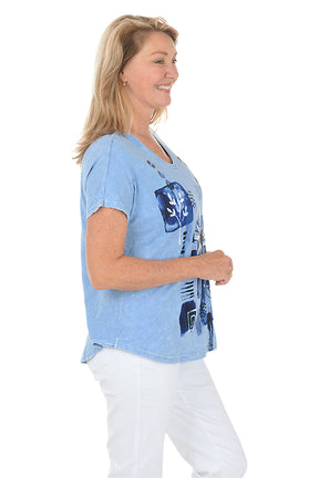 Woman wearing a blue floral graphic t-shirt against a white background. Side shot.