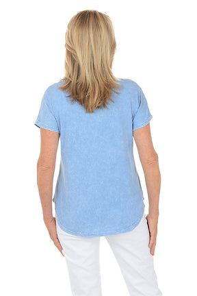 Woman wearing a blue floral graphic t-shirt against a white background. Back shot.