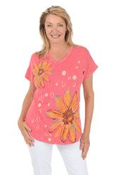 Woman wearing a pink t-shirt with orange floral designs on a white background.
