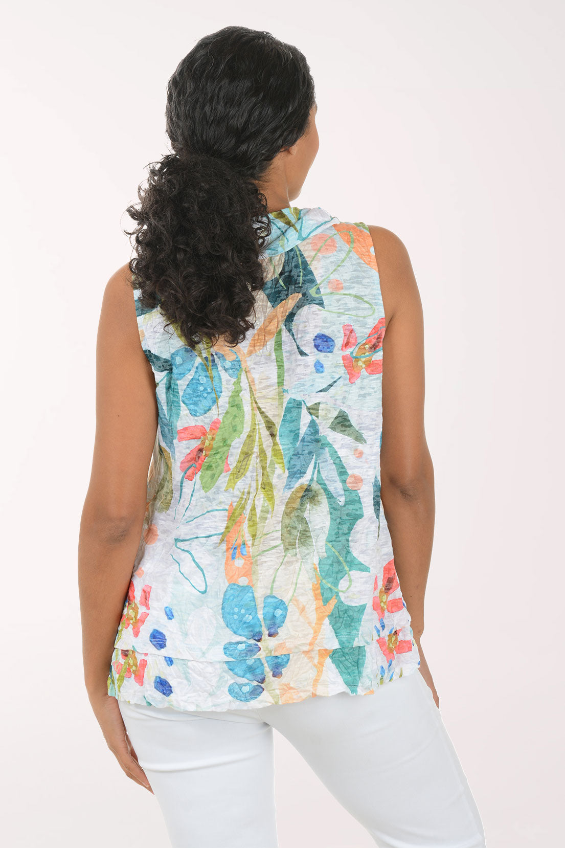 Woman wearing a colorful floral sleeveless top against a white background