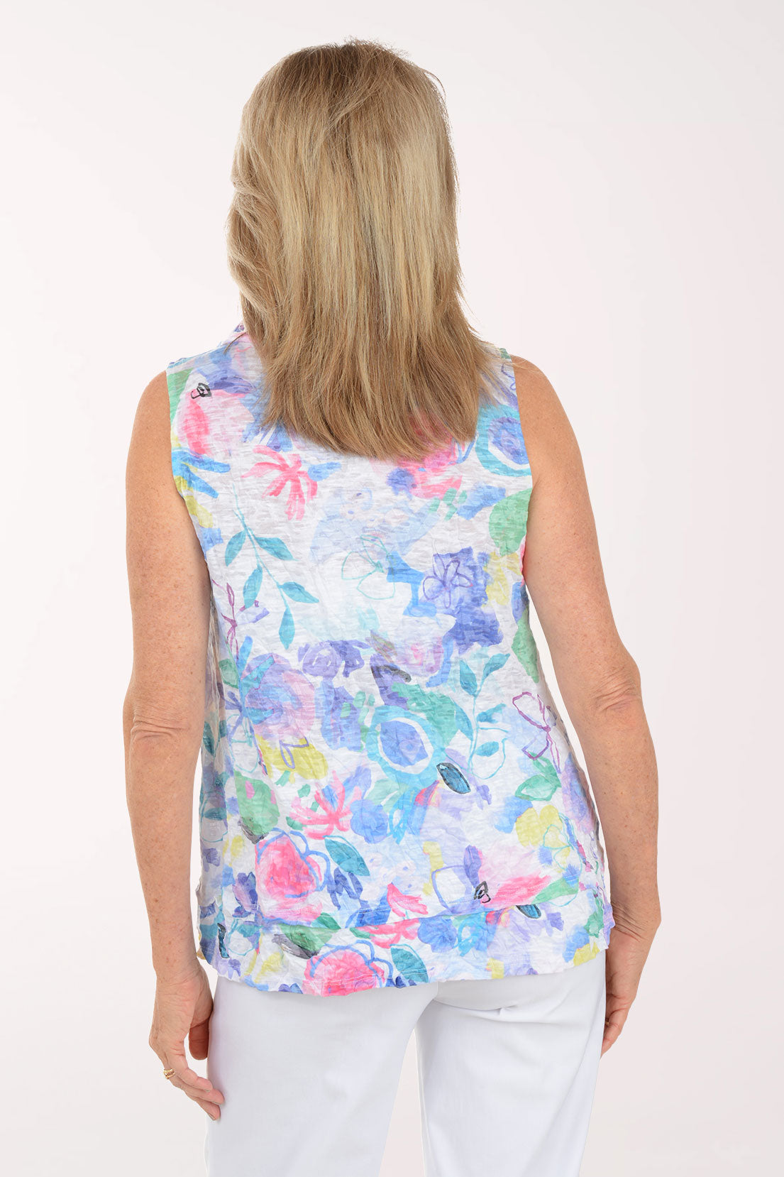 Woman wearing a colorful floral sleeveless top against a white background