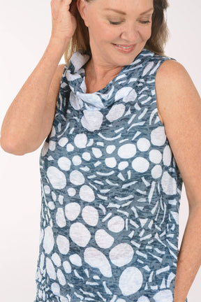 Woman wearing a sleeveless patterned top against a white background