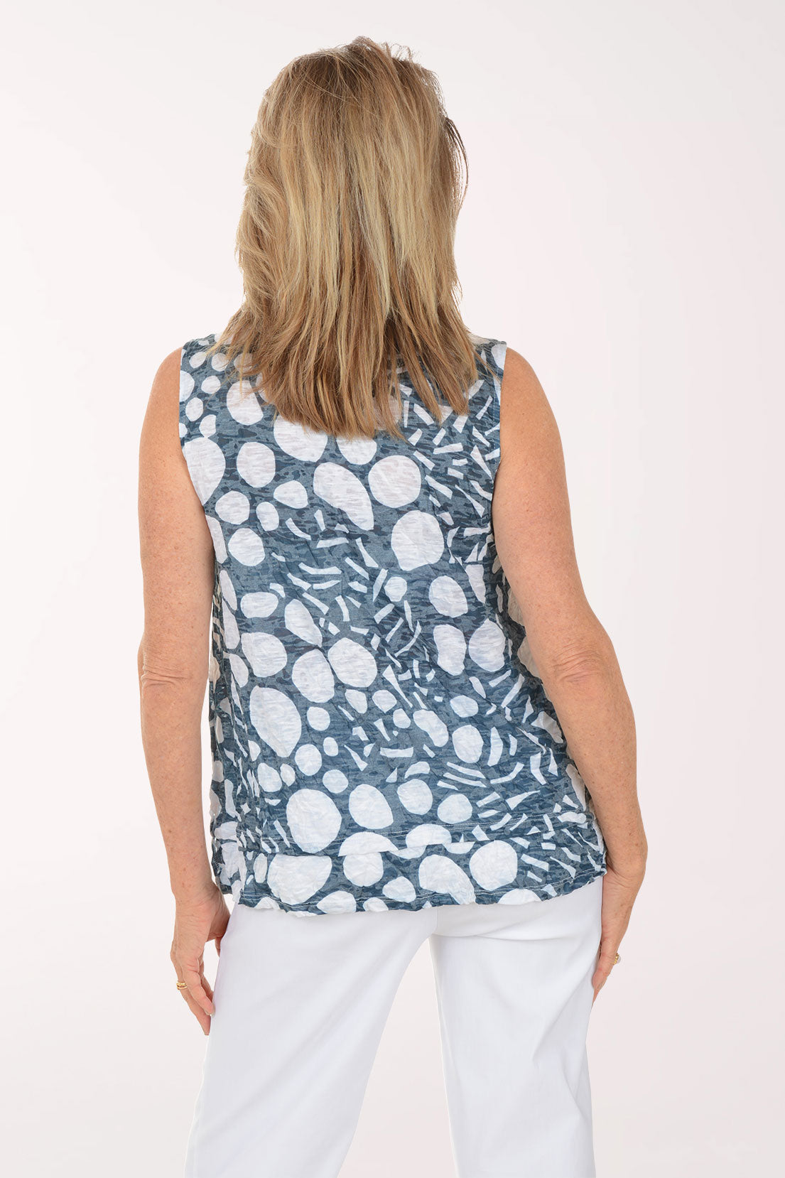 Woman wearing a sleeveless patterned top against a white background
