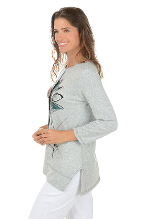 Woman wearing a gray sweater with a colorful butterfly design on a white background.  Side shot.