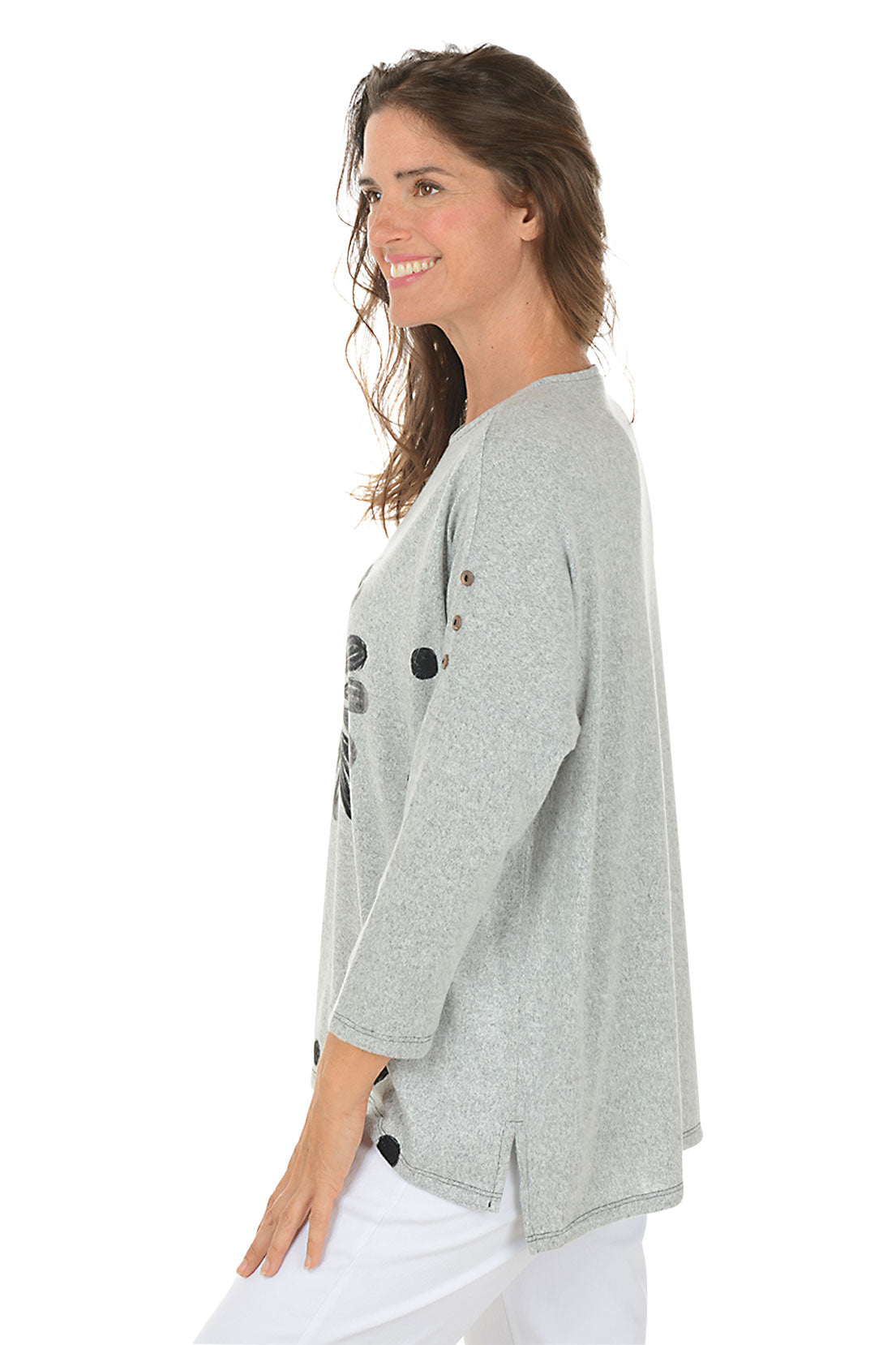 Woman wearing a gray sweater with a floral design on a white background. Side shot.