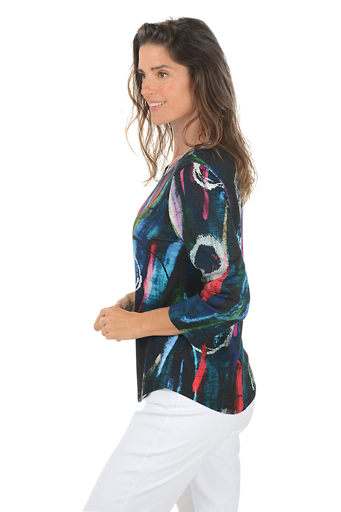 Woman wearing a colorful abstract patterned top on a white background. Side shot.