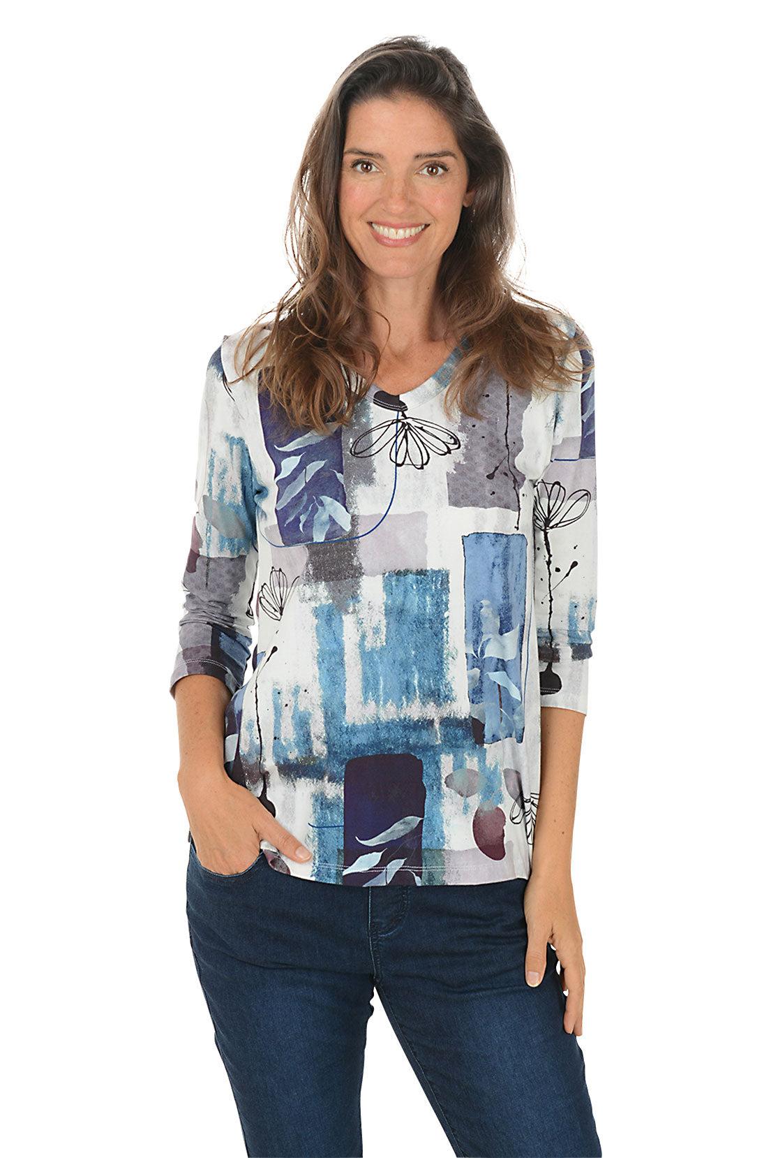 Woman wearing a colorful patterned top with blue jeans on a white background.