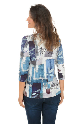 Woman wearing a colorful patterned top with blue jeans on a white background. Back shot.