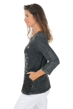 Woman wearing a dark denim shirt with floral embroidery on a white background. Side shot.