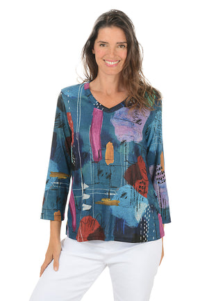 Woman wearing a colorful abstract patterned top on a white background. Second front shot.