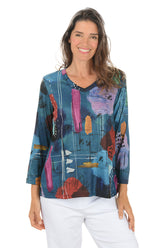 Woman wearing a colorful abstract patterned top on a white background.