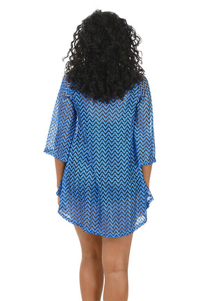 Woman wearing a blue chevron patterned cover-up on a white background. Back shot.