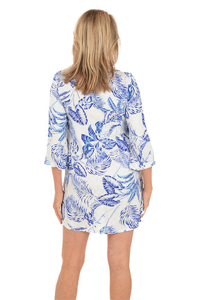 Woman wearing a blue and white patterned dress on a white background. Back shot.