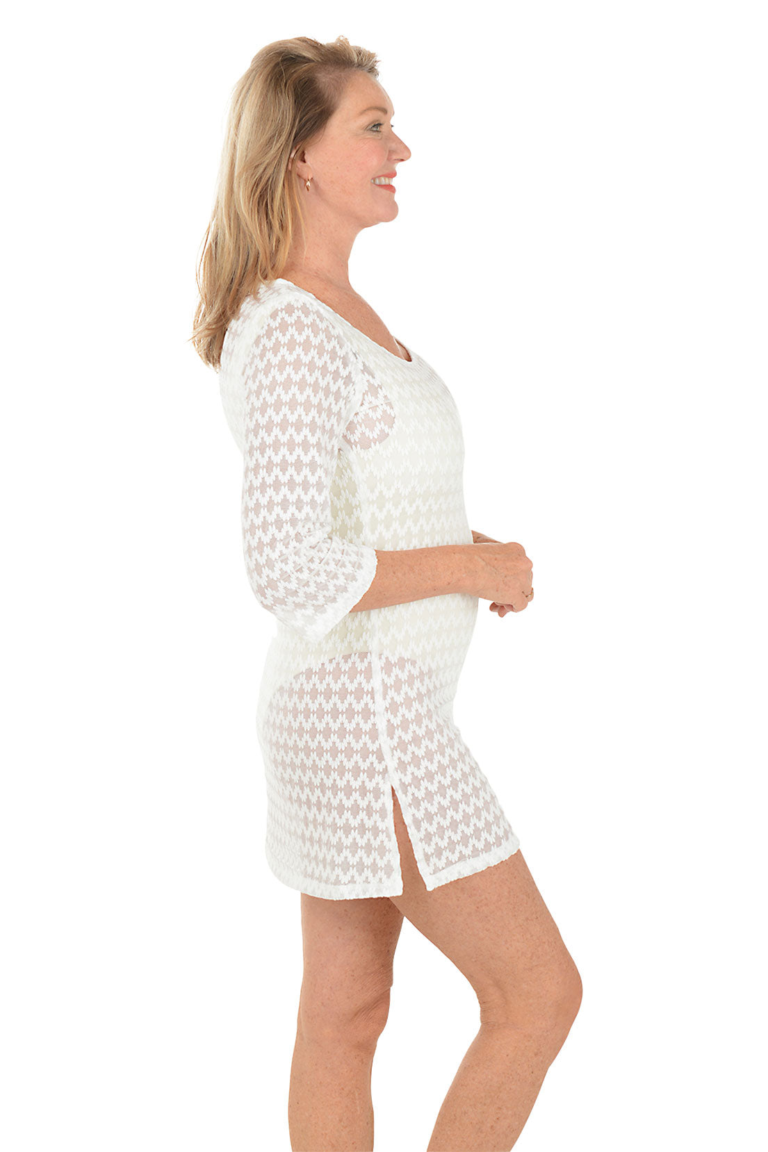 Woman wearing a white lace dress on a white background. Side shot.