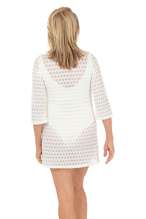 Woman wearing a white lace dress on a white background. Back shot.