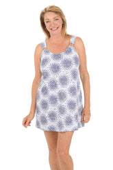 Woman wearing a white dress with blue floral pattern on a white background.