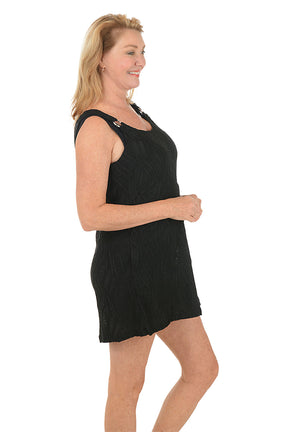Woman wearing a black sleeveless dress on a white background. Side shot.
