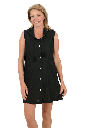 Woman wearing a black sleeveless dress with buttons on a white background.