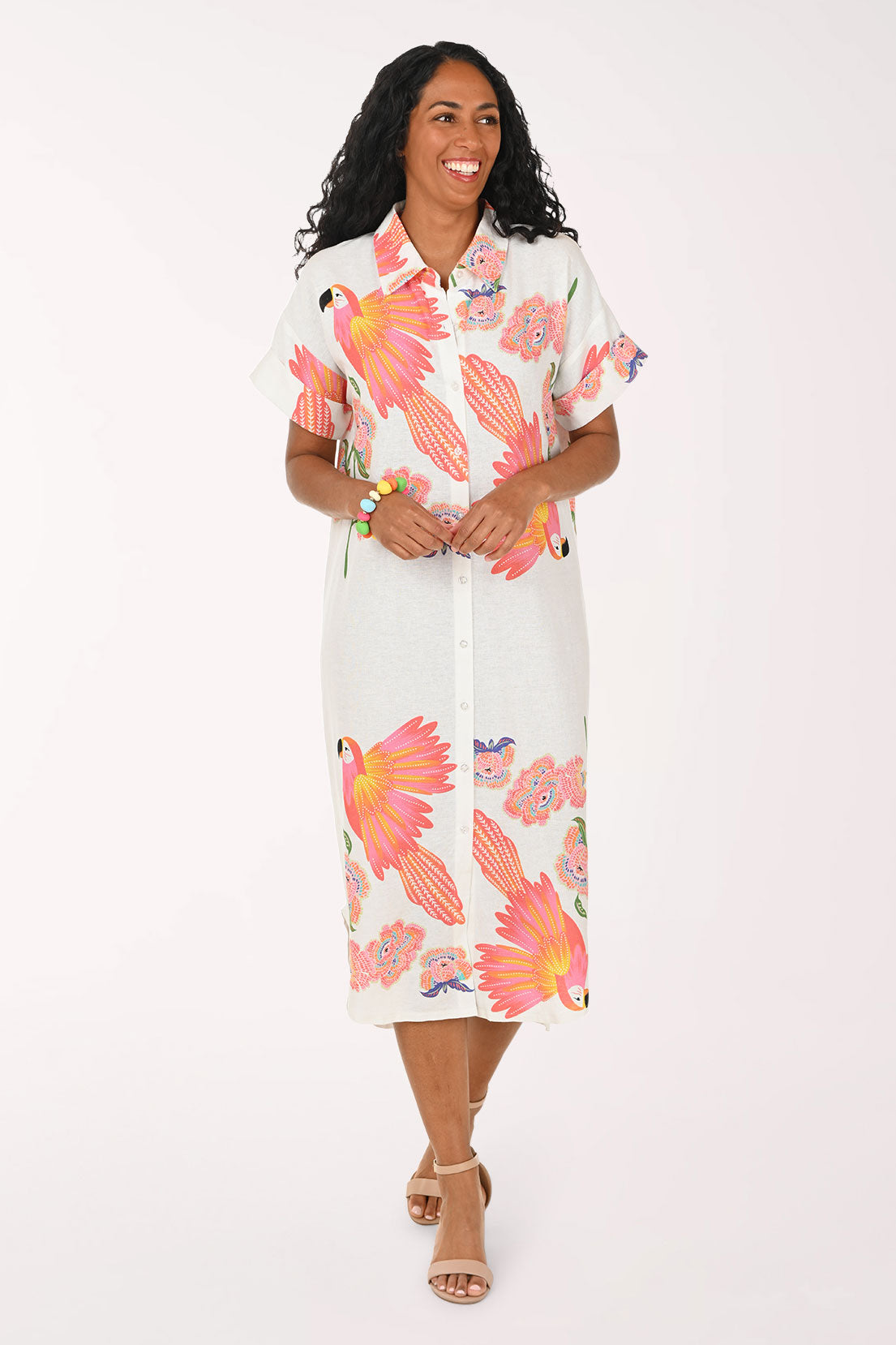 Woman wearing a white multi dress with a parrot print.