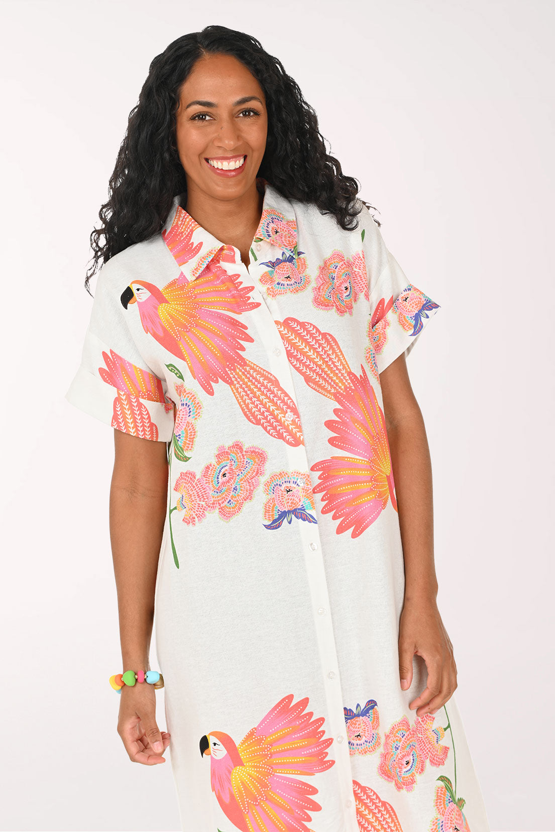 Woman wearing a white multi dress with a parrot print.