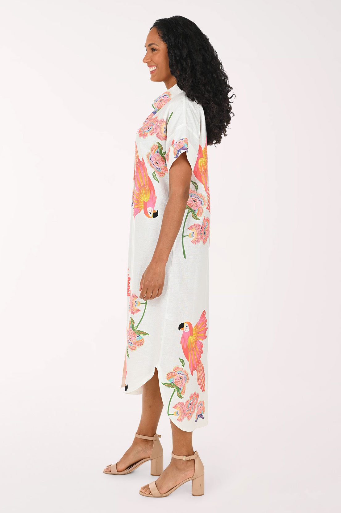 Woman wearing a white multi dress with a parrot print.