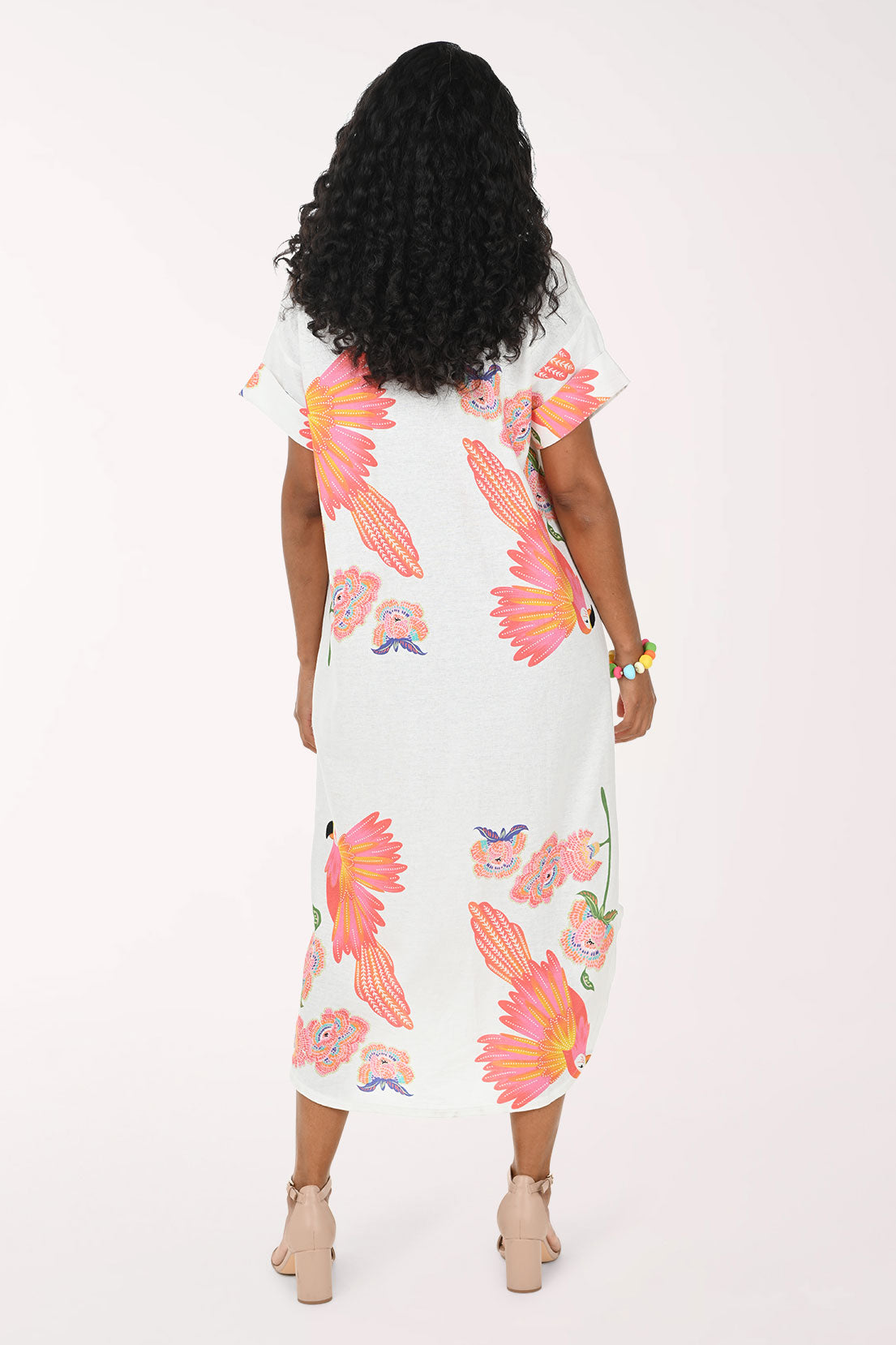 Woman wearing a white multi dress with a parrot print.