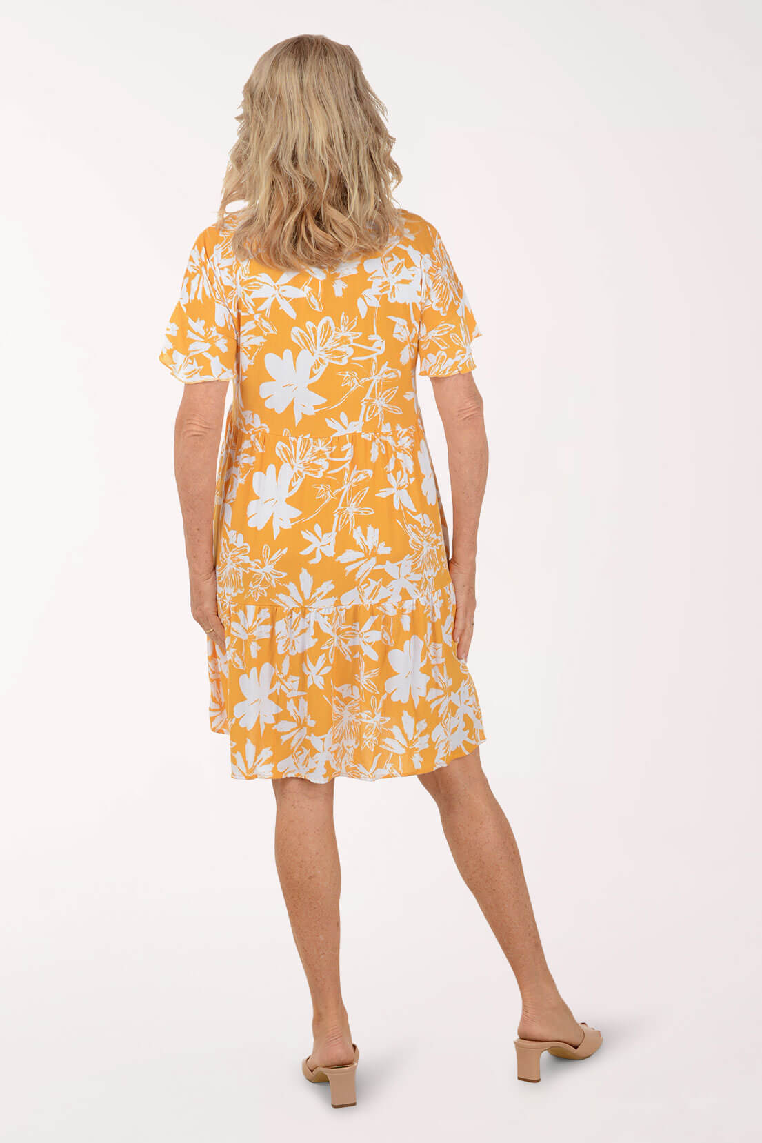 Woman wearing a yellow floral dress on a white background